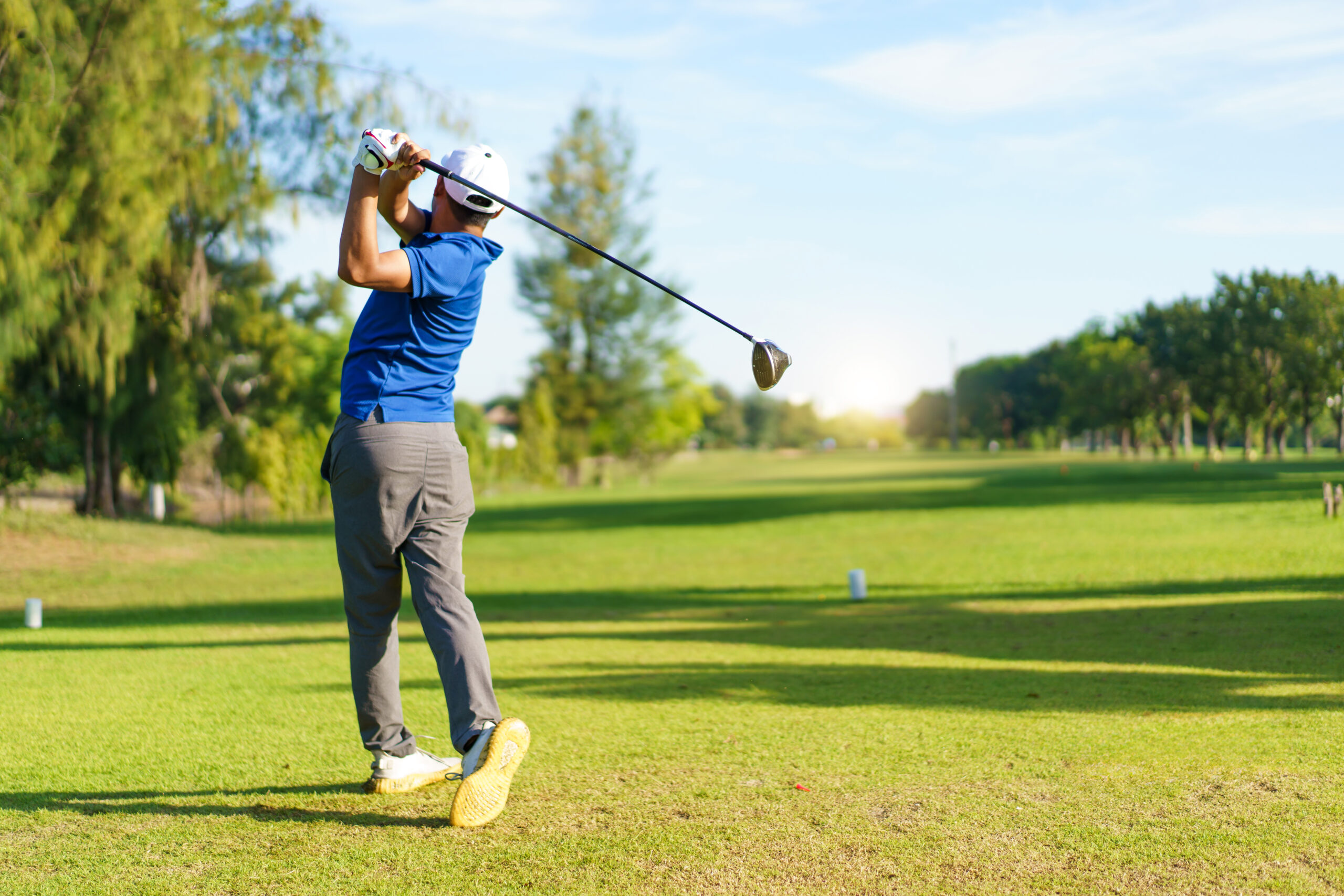 Male amateur golfer is enjoy playing golf at golf course in morning, he is showing his beautiful swing during tee off. Man playing golf.